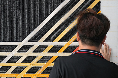 Personnalisation tapis touffé résidentiel: Un artisan vérifie la qualité d'un tapis noir sur mesure aux lignes abstraites simples pour intérieur