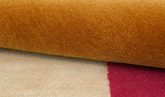 Gros plan d'un tapis touffeté géométrique en tons or, beige et bordeaux