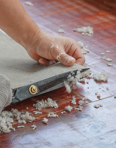 Artisan coupant les fils excédentaires du bord d'un tapis touffeté sur mesure