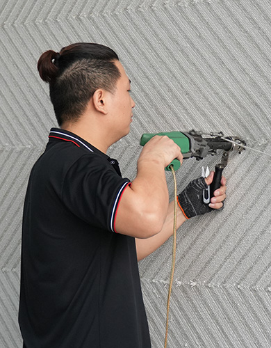 Artisan utilisant un pistolet à touffer pour créer un tapis personnalisé