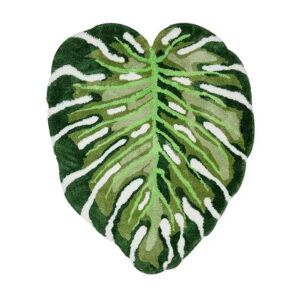 Tapis en laine tuftée forme feuille de monstera avec détails sculptés en différentes nuances de vert et découpes blanches caractéristiques.