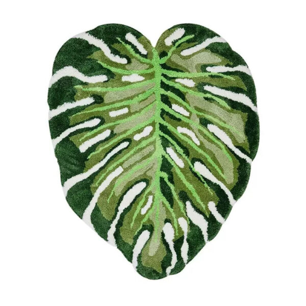 Tapis en laine tuftée forme feuille de monstera avec détails sculptés en différentes nuances de vert et découpes blanches caractéristiques.